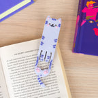Flexible grey cat reading light bookmark sitting inside an open book.