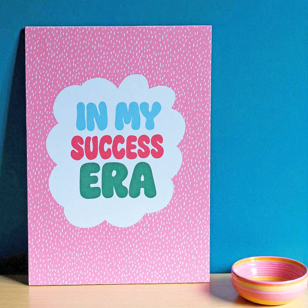 Colourful In My Success Era A5 print with blue, pink and green lettering on a bright pink patterned background.