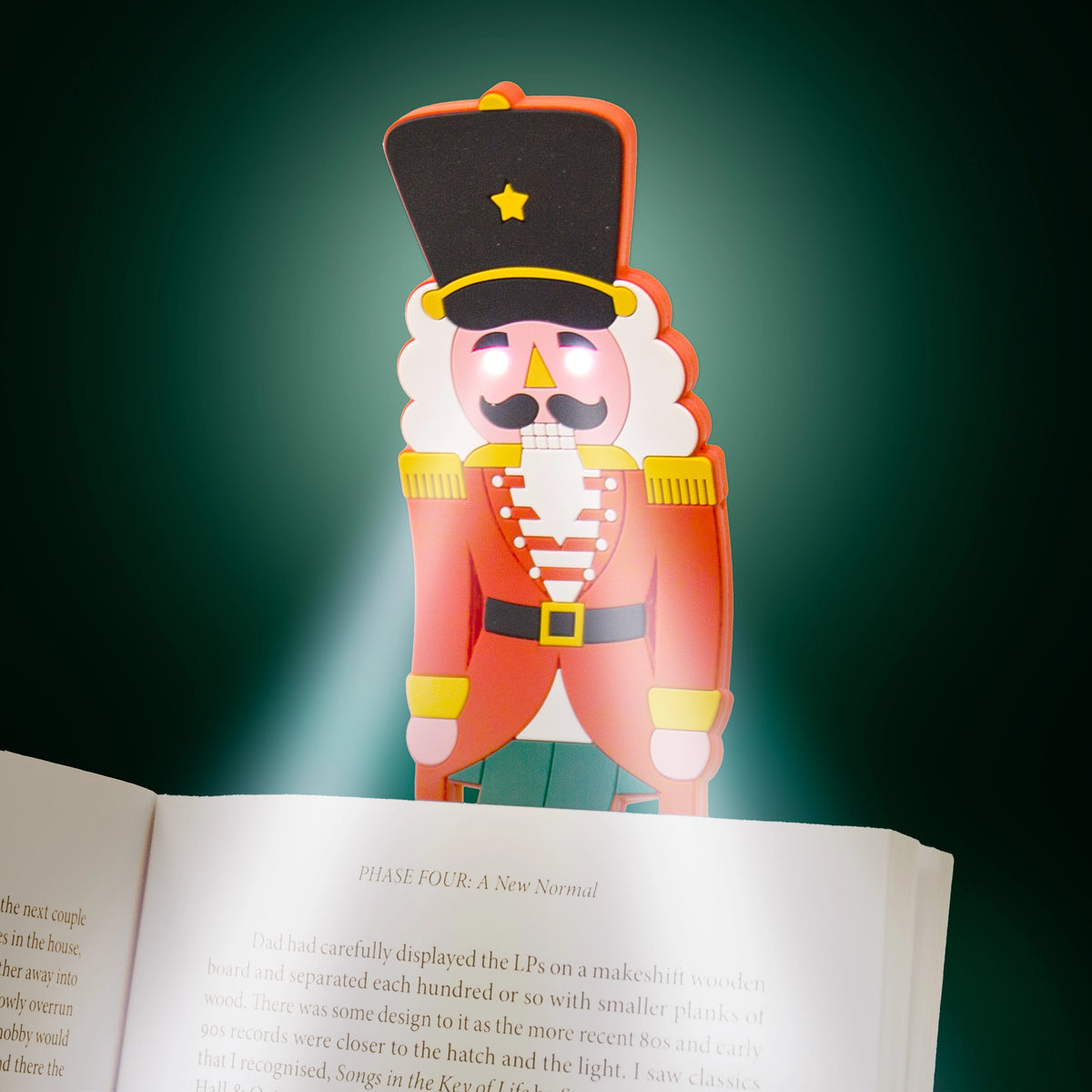 Nutcracker reading light glowing over the pages of an open book in the dark.
