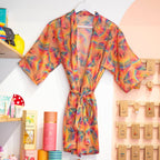 Bright tropical leaf print kimono robe displayed with its matching tie belt in a colourful boutique setting.