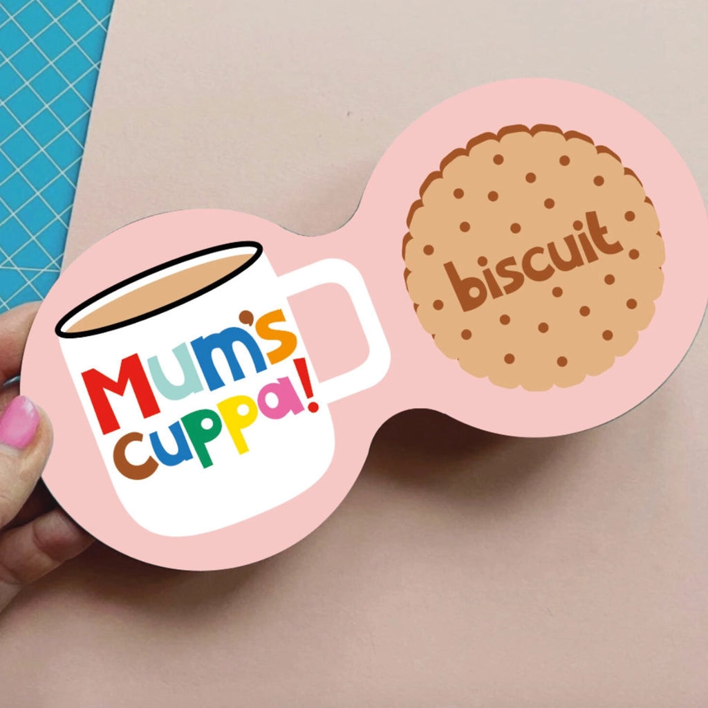 Mum’s Cuppa and biscuit double coaster held up inside a colourful independent shop.