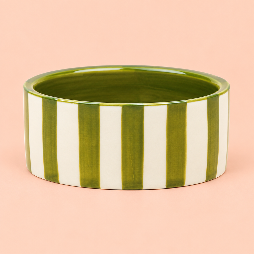 Hand painted green and cream striped ceramic wine bottle coaster on a soft peach background.
