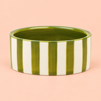 Hand painted green and cream striped ceramic wine bottle coaster on a soft peach background.
