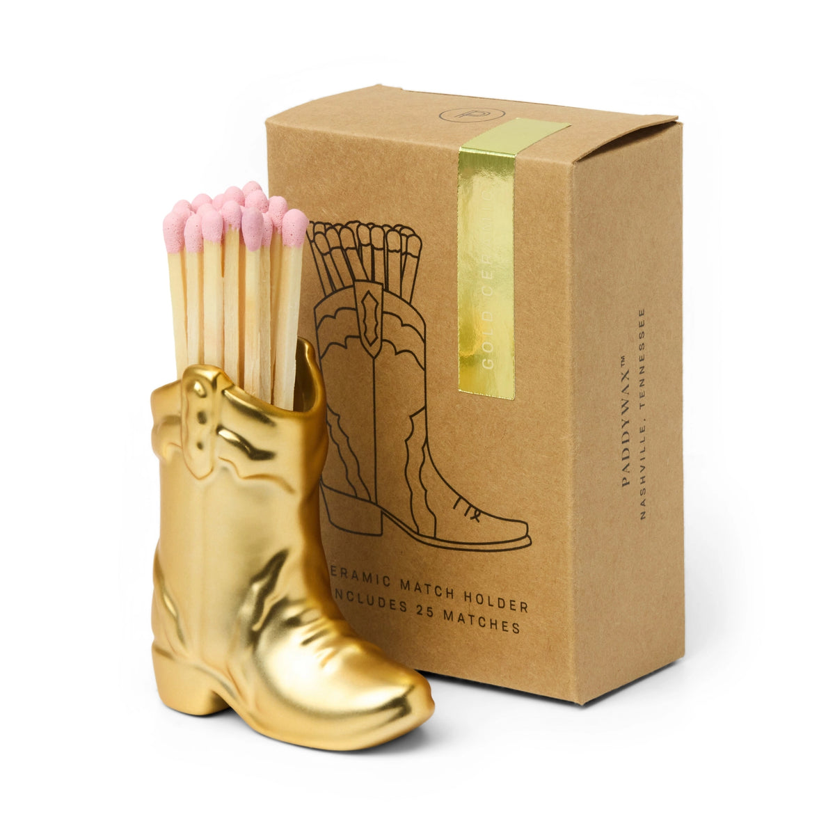 Gold ceramic cowboy boot match holder with pink tipped matches beside its kraft gift box.
