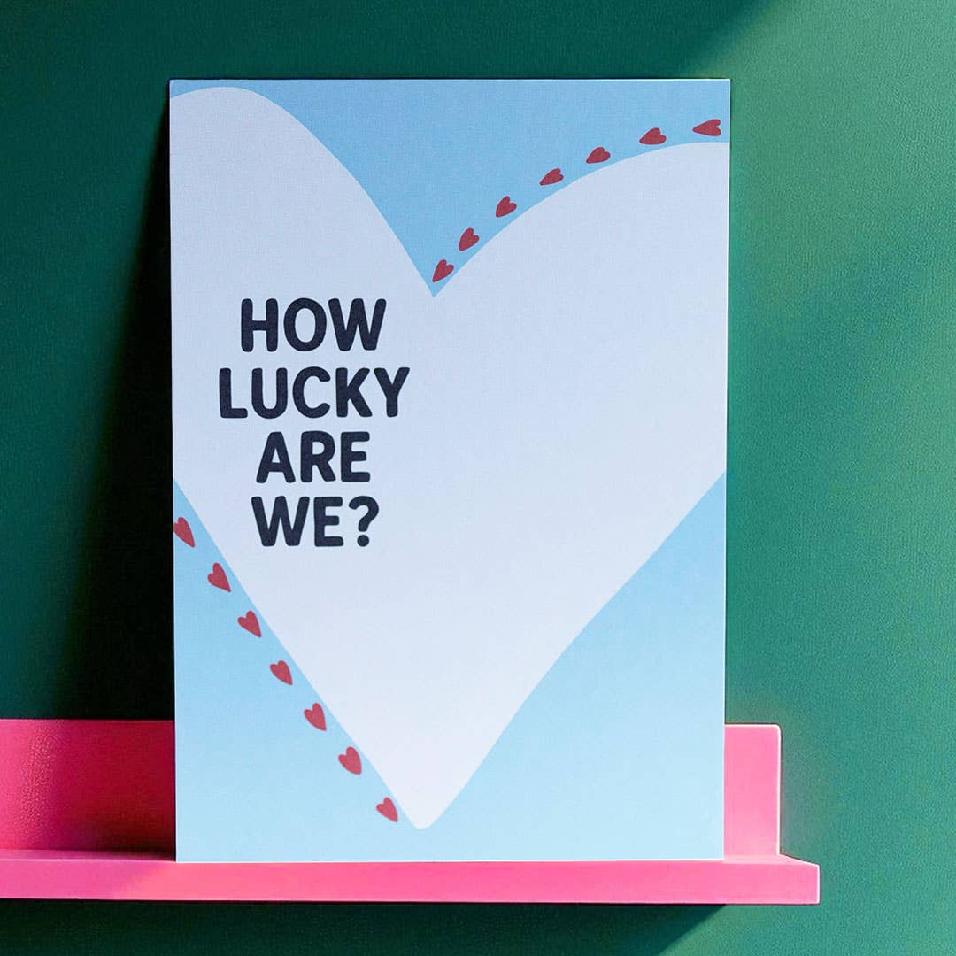 Uplifting How Lucky Are We? A5 art print with a large white heart, pastel blue background and cheerful red heart details.