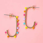 Gold tone open statement earrings decorated with pink, yellow, orange, turquoise and lilac dots.