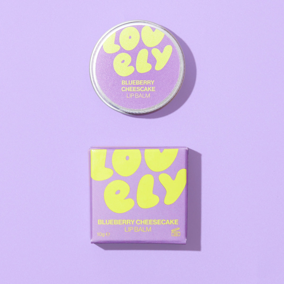 Blueberry Cheesecake Lip Balm 10g tin and purple gift box on a lilac background.