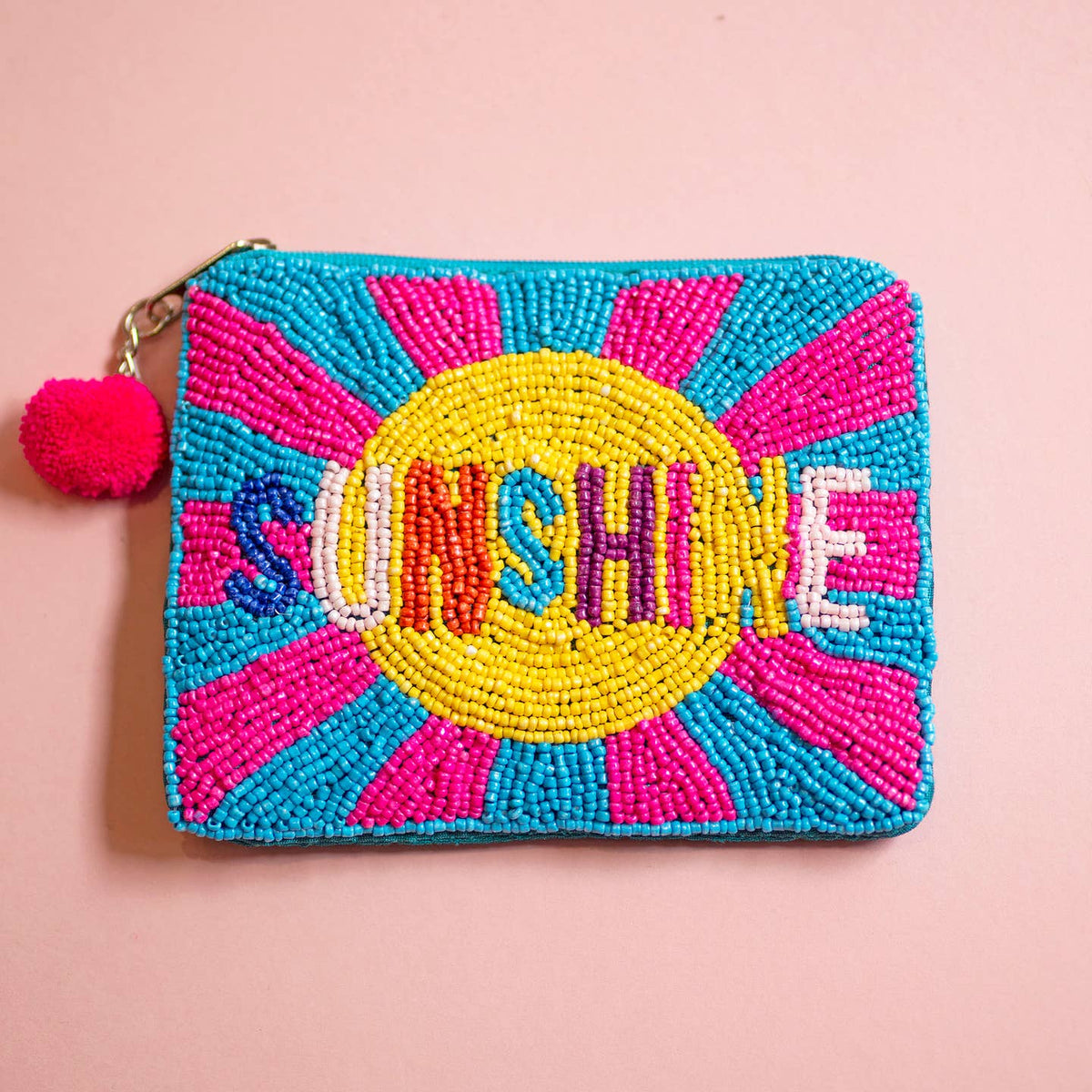 Colourful beaded zip pouch with multicoloured ‘SUNSHINE’ lettering, turquoise, pink and yellow radiating design and pink pom pom.