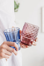Blue and purple textured fish drinking glasses held in hands.
