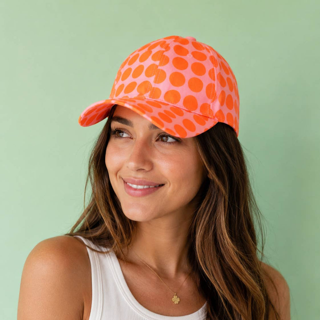 Joyful pink and orange polka dot baseball cap worn for a bright, playful pop of everyday colour.