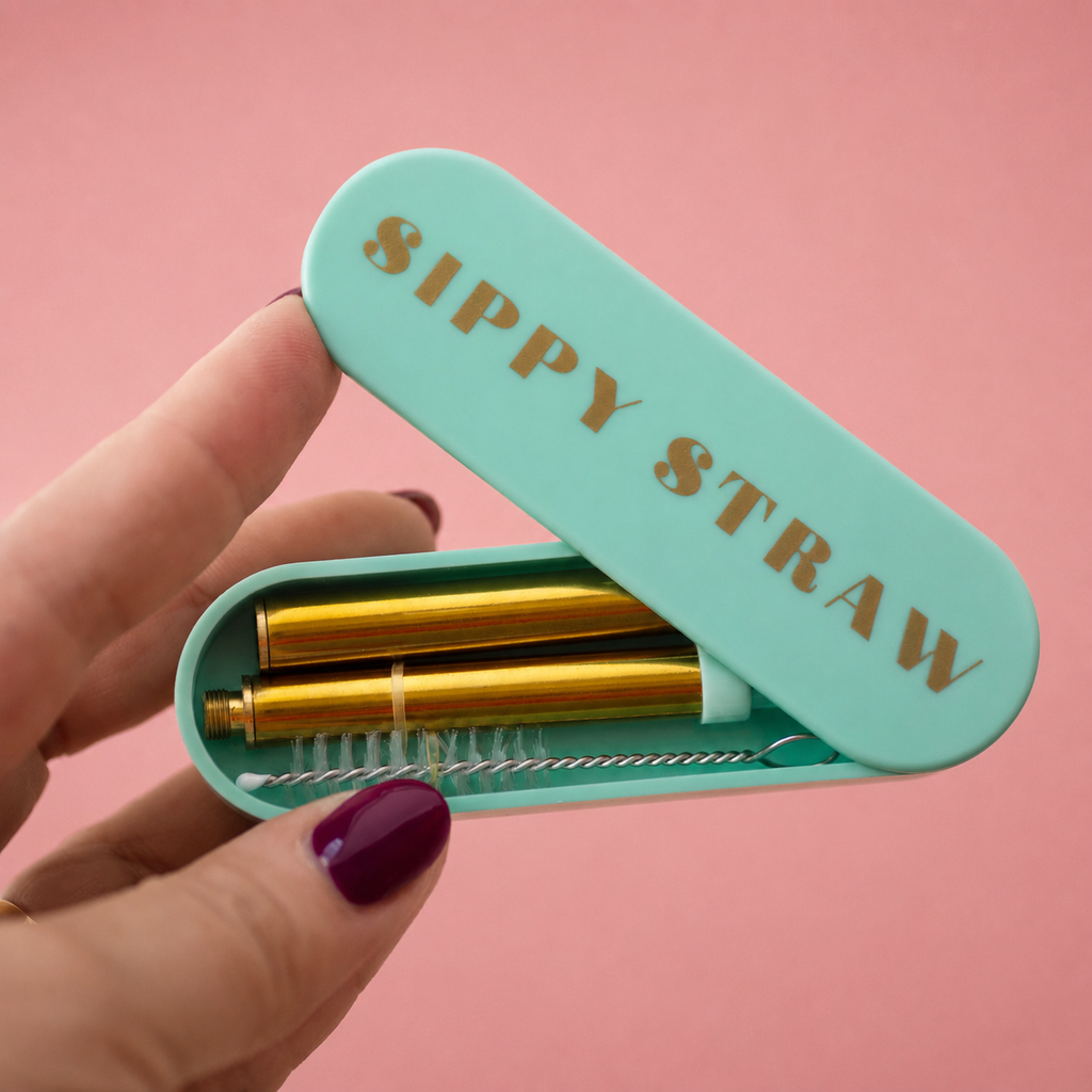 Mint green Sippy Straw travel case held open to show a gold coloured reusable straw and cleaning brush inside