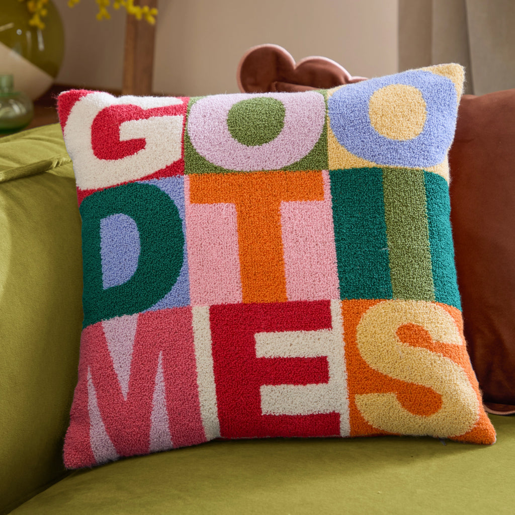 Colourful Good Times tufted cushion with bold retro lettering styled on a green sofa.