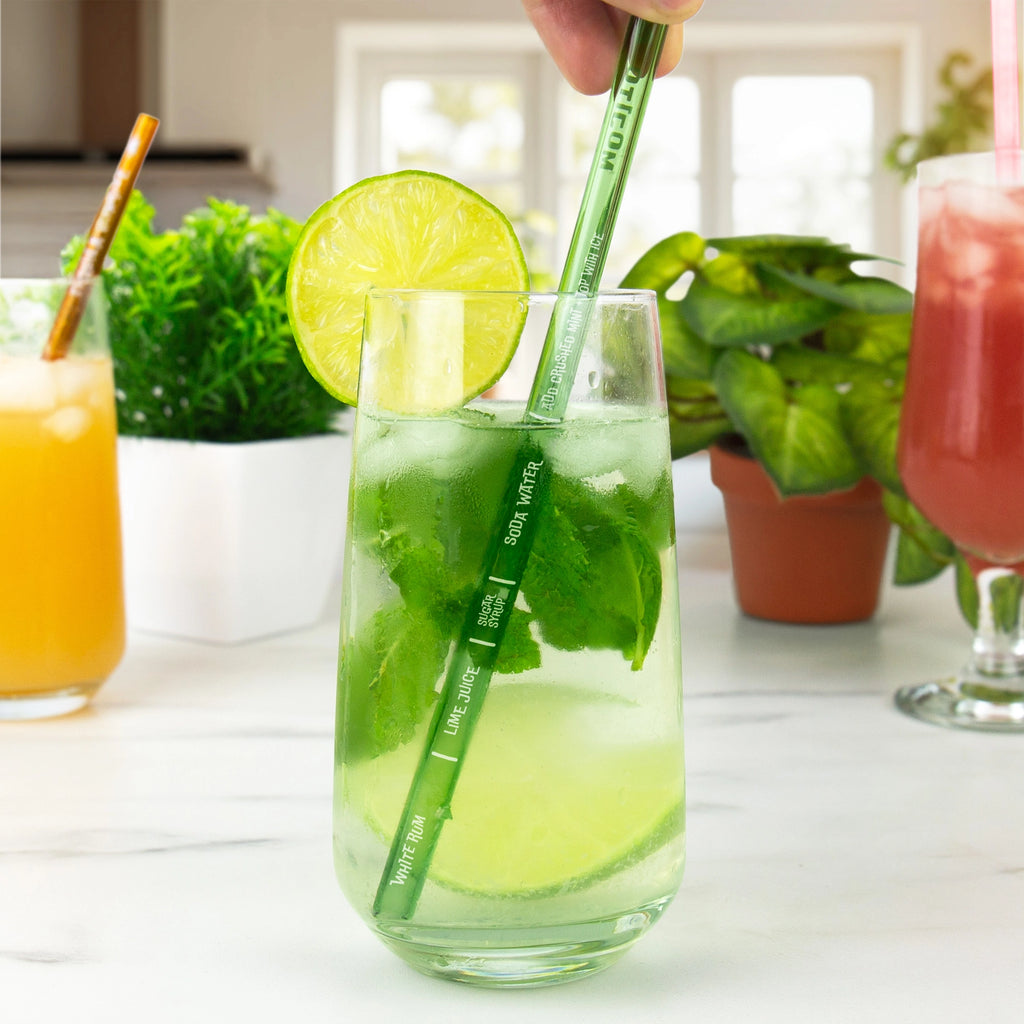 Green Mojito recipe glass straw being used to mix a cocktail with lime and mint.
