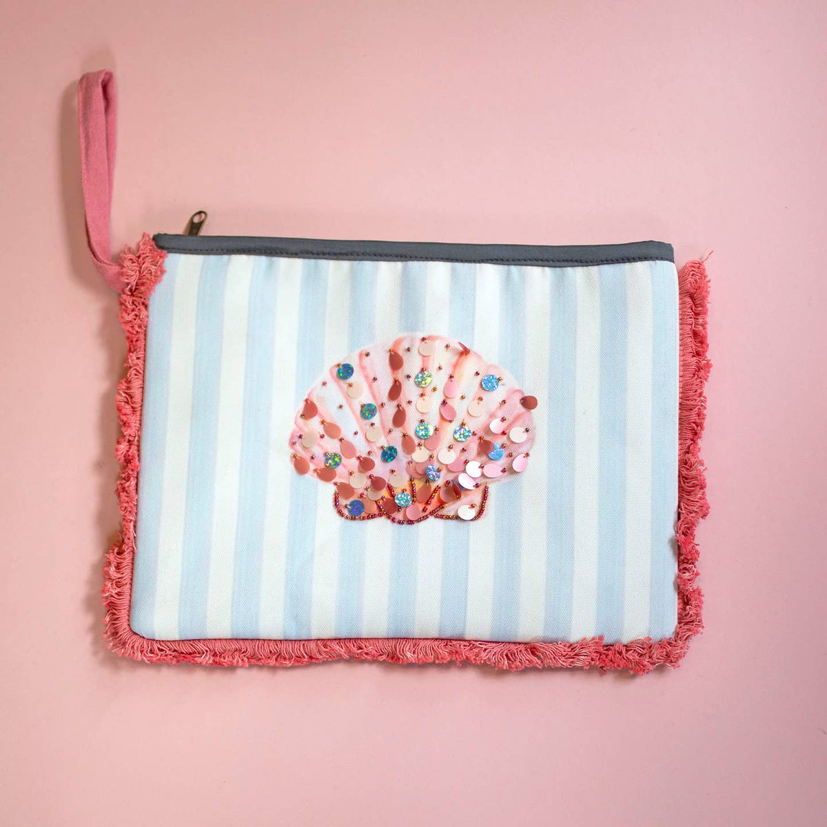 Bright blue and white striped clutch bag with a shimmering pink embellished shell, coral frayed edging and matching wrist strap.