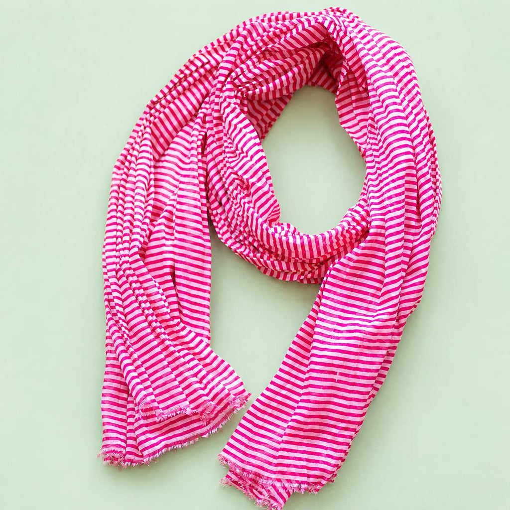 Joyful pink and white striped cotton scarf loosely arranged to show its bright pattern and softly frayed edges.