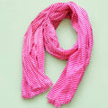 Joyful pink and white striped cotton scarf loosely arranged to show its bright pattern and softly frayed edges.