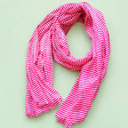 Joyful pink and white striped cotton scarf loosely arranged to show its bright pattern and softly frayed edges.