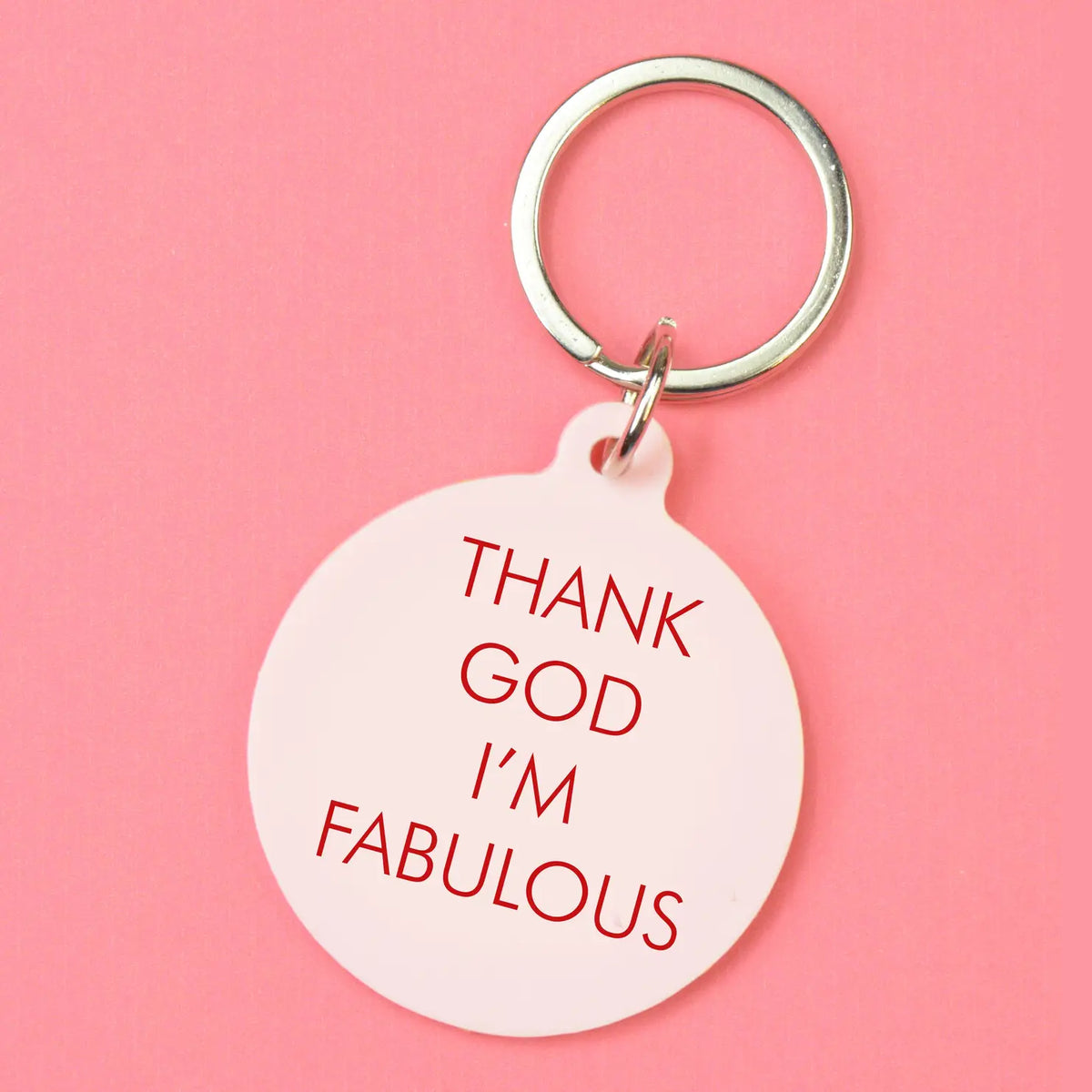 Pale pink round keyring with red Thank God I'm Fabulous lettering and silver-tone metal keyring attachment.