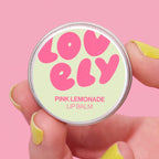 Pink Lemonade Lip Balm tin held in a hand against a pink background.
