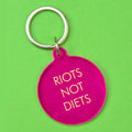 Hot pink round statement keyring with pale yellow Riots Not Diets lettering and silver-tone metal keyring attachment.