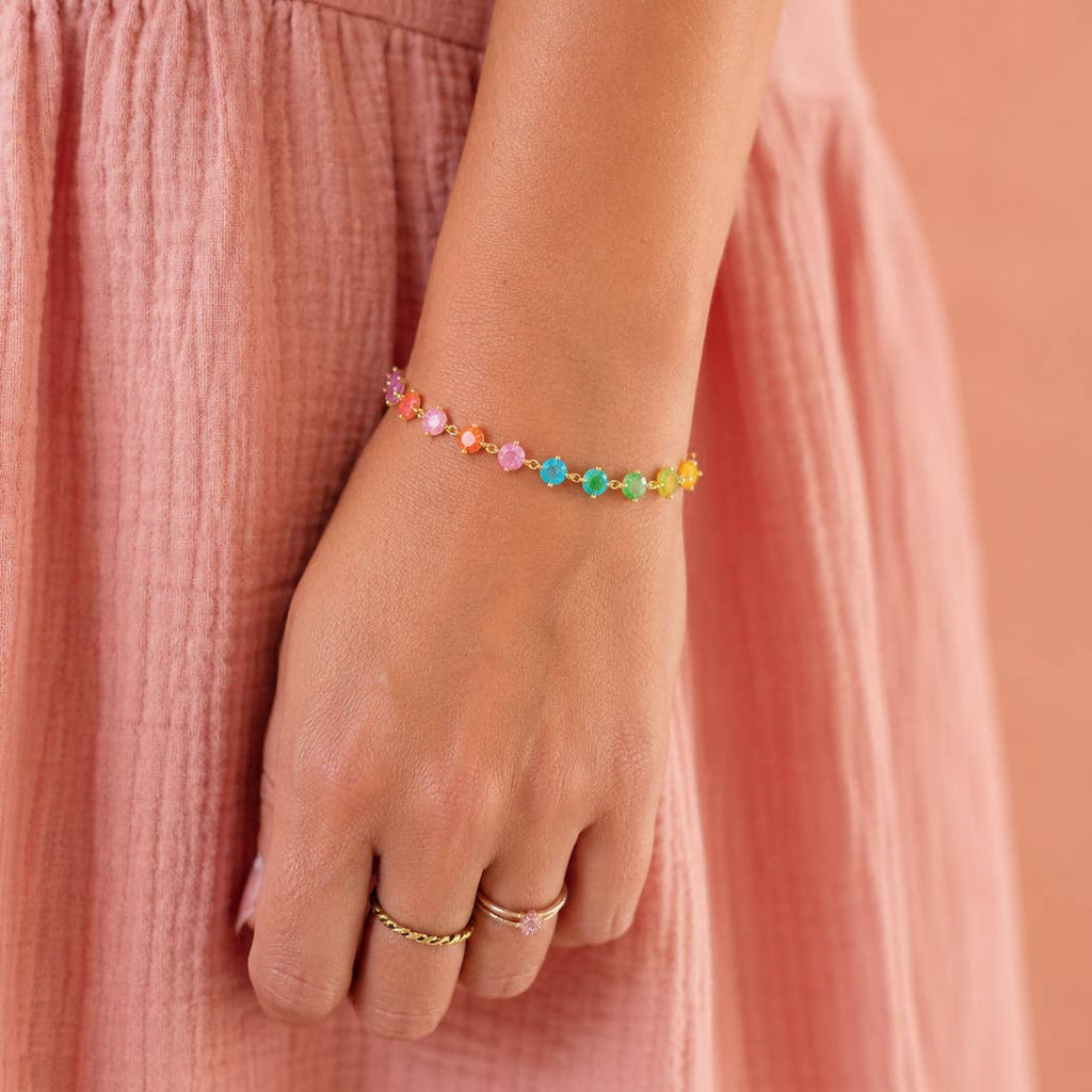 Rainbow frosted crystal gold chain bracelet worn on the wrist with a pink dress.