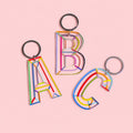 Colourful acrylic initial keychains in letters A, B and C with multicoloured line details and silver-tone rings.