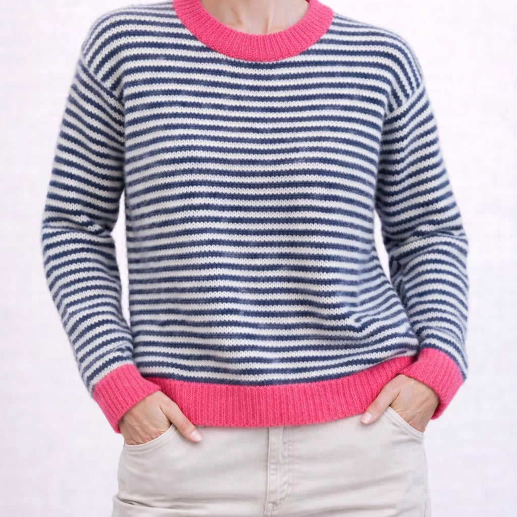 Woman wearing a relaxed black and white striped jumper with bright pink contrast trim.