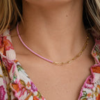 Two tone pale pink and gold plated chain necklace worn with a colourful floral top.