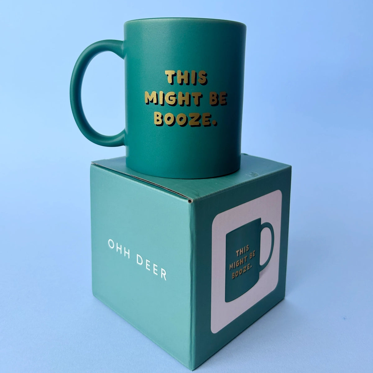 Green This Might Be Booze ceramic mug displayed on its matching green gift box against a pale blue background.