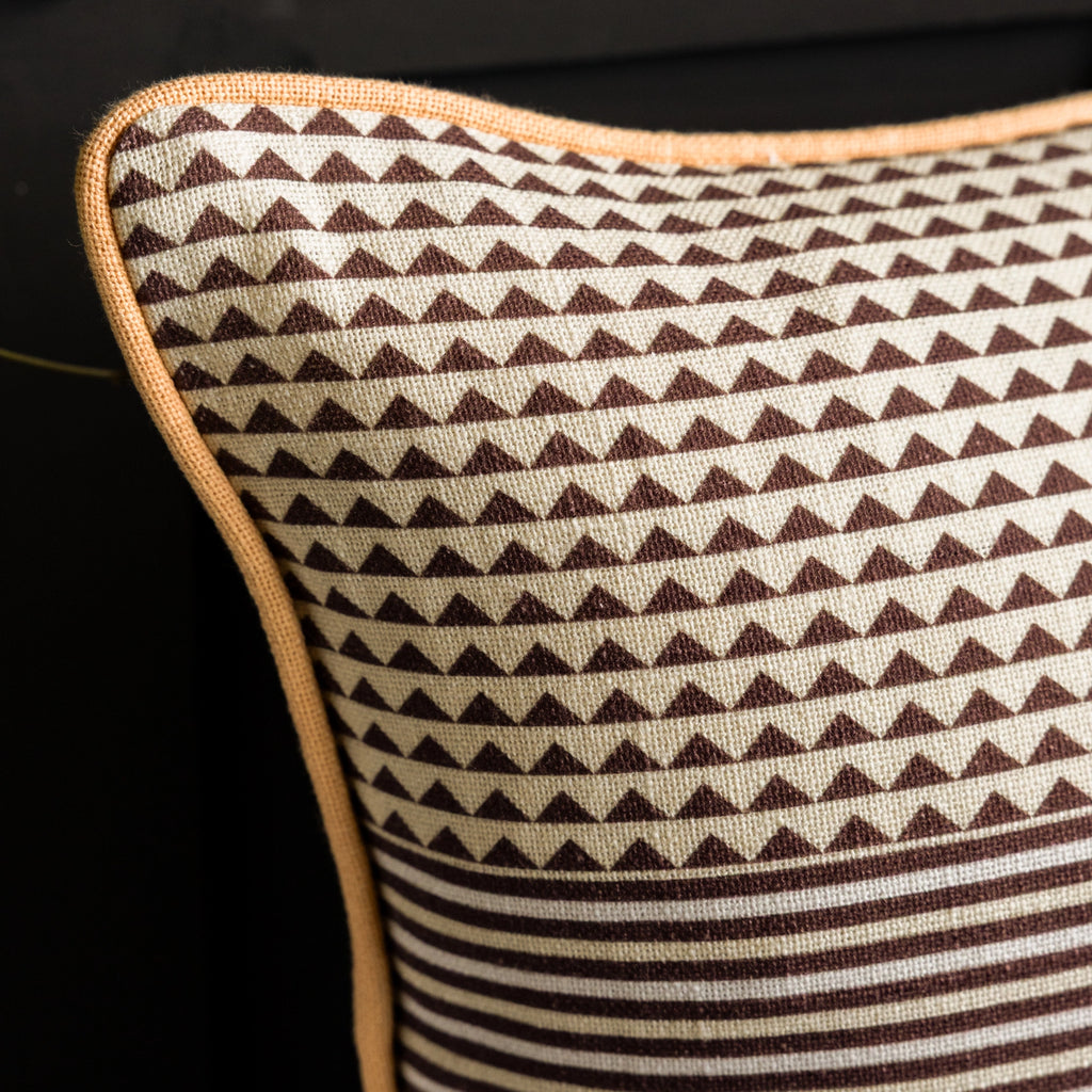 Reverse of cotton cushion featuring brown geometric and striped patterns with contrasting peach piping.