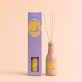 Lemon Soda reed diffuser in a peach bottle with natural reeds and lilac gift box on a soft peach background.