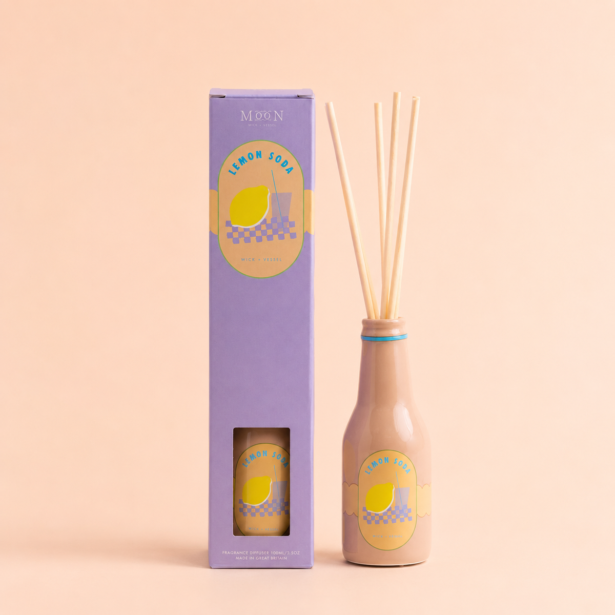 Lemon Soda reed diffuser in a peach bottle with natural reeds and lilac gift box on a soft peach background.