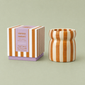 Sienna Sunset soy wax candle in a caramel and cream striped ceramic vessel beside its matching striped box.