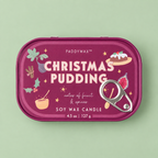 Berry pink Christmas Pudding soy wax candle tin with festive illustrations and silver pull ring on a pale green background.