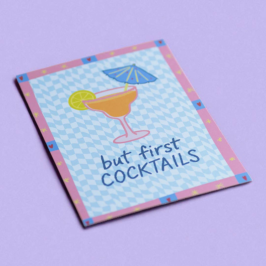 Playful But First Cocktails A5 print with blue checkerboard pattern and pink border, displayed on a soft lilac background.