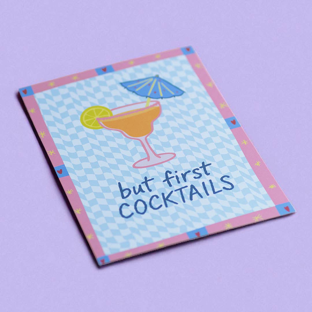 Playful But First Cocktails A5 print with blue checkerboard pattern and pink border, displayed on a soft lilac background.