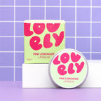 Pink Lemonade Lip Balm tin and bright pink and green box displayed against a lilac tiled background.