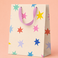 Cream gift bag scattered with colourful stars in pink, blue, yellow, coral, lilac and mint with soft pink ribbon handles.