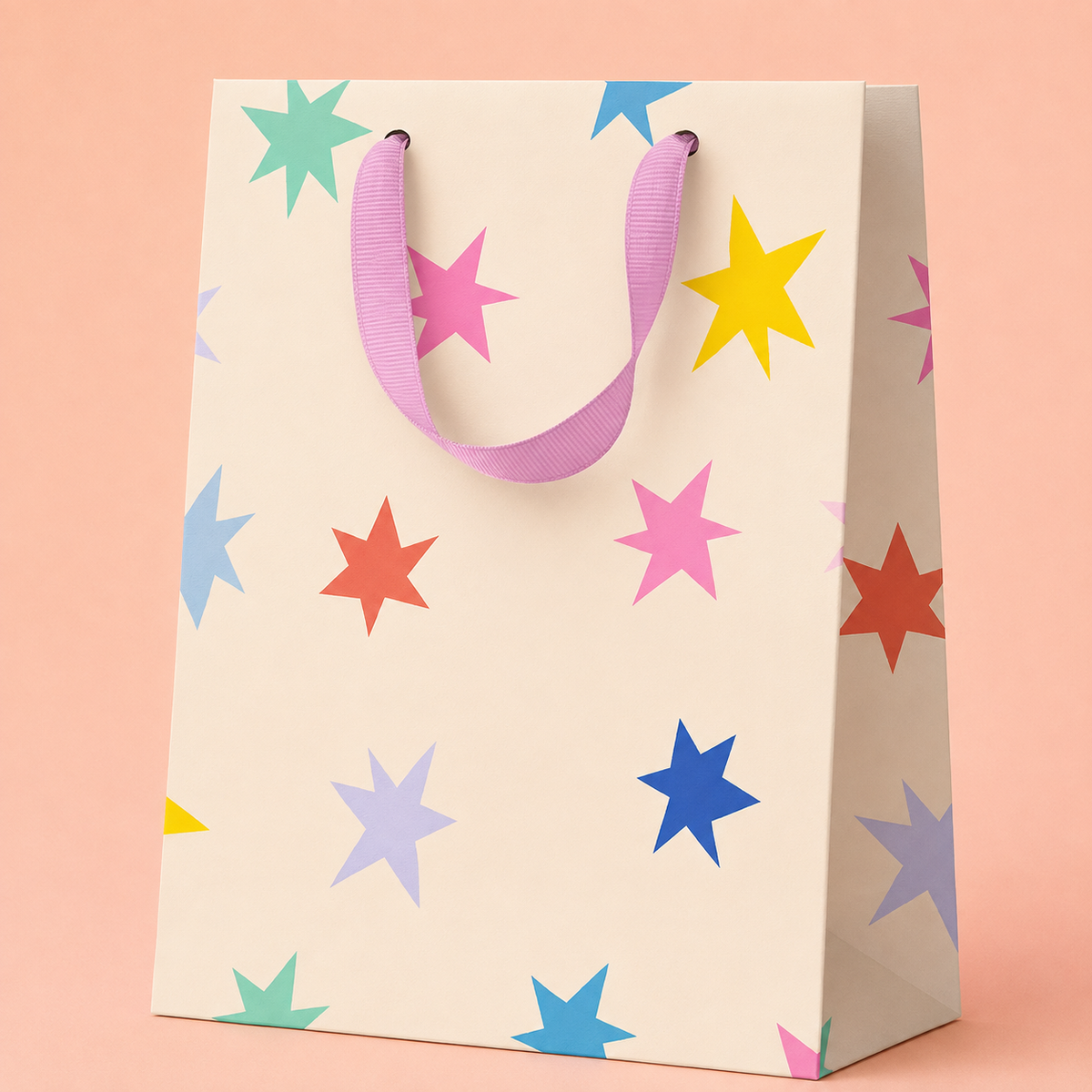 Cream gift bag scattered with colourful stars in pink, blue, yellow, coral, lilac and mint with soft pink ribbon handles.