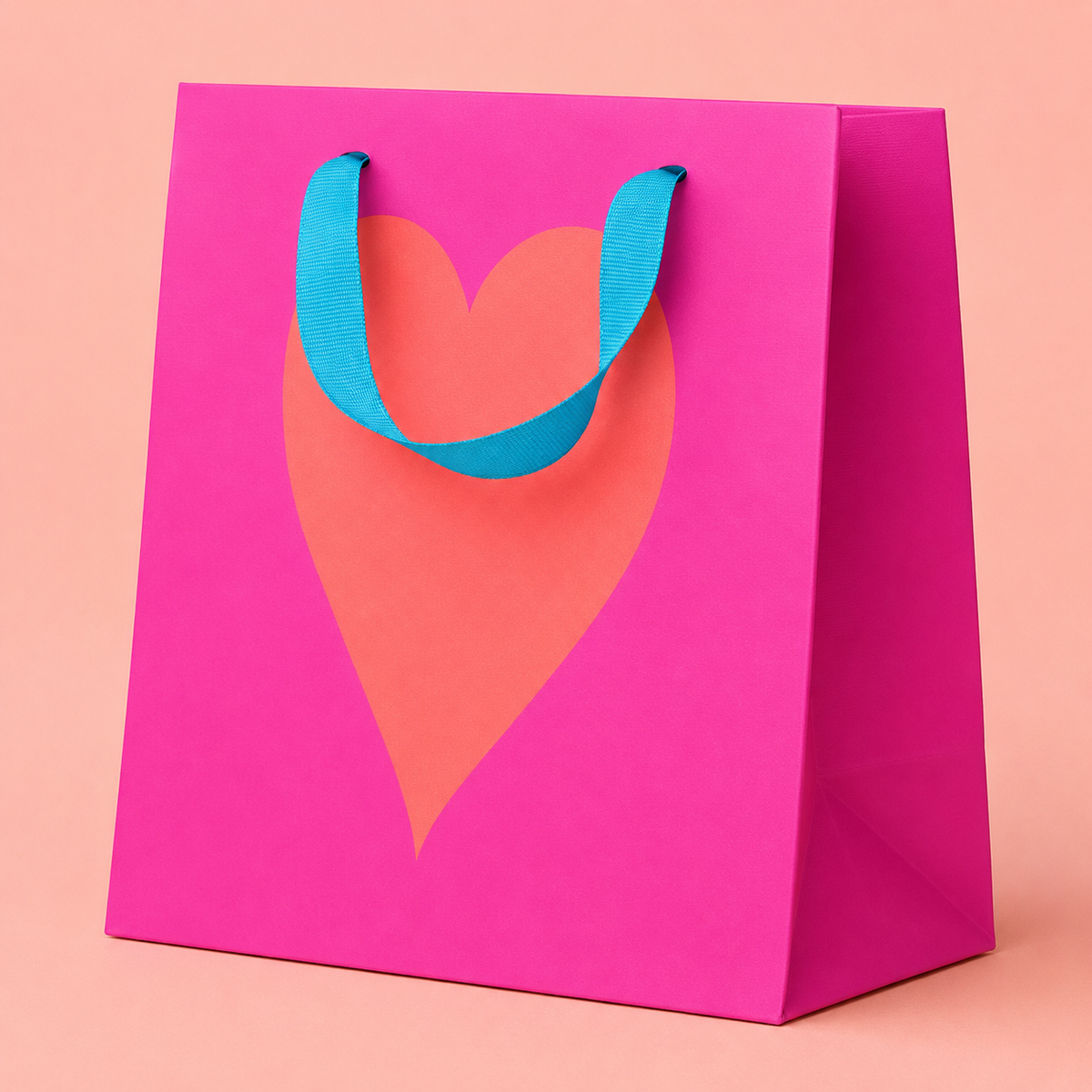 Neon pink square gift bag with a large coral heart and contrasting bright blue ribbon handles.

