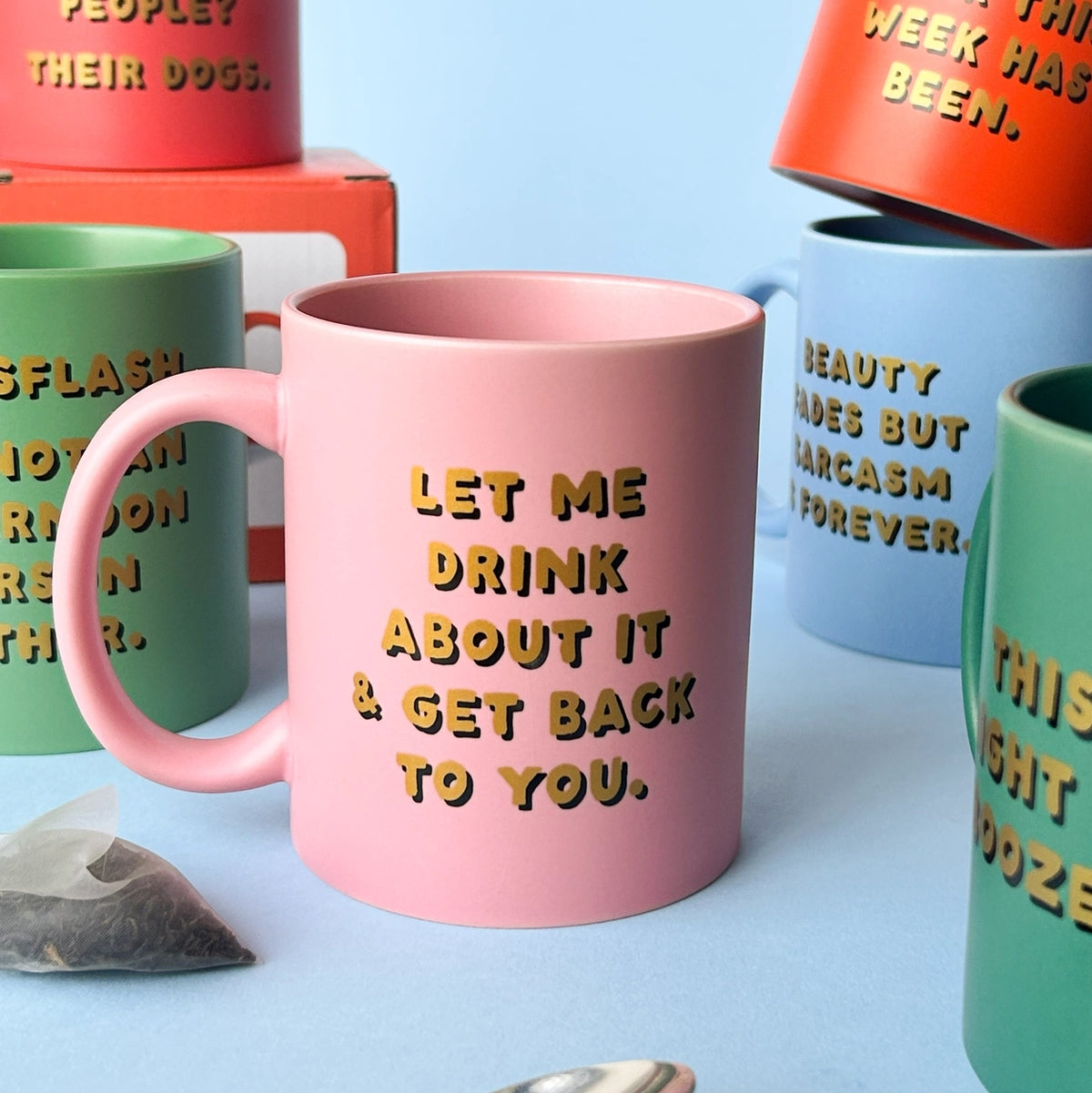 Pink Ohh Deer mug reading Let Me Drink About It & Get Back To You, styled with colourful slogan mugs.