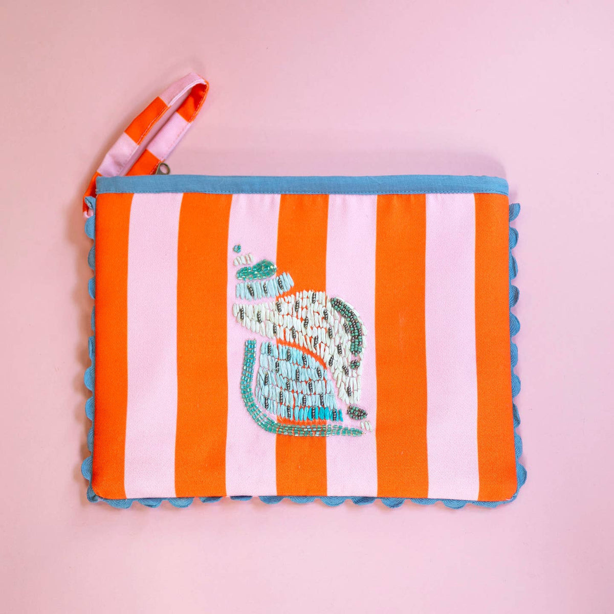 Colourful orange and pink striped clutch bag with intricate beaded shell motif, blue edging and matching wrist strap.