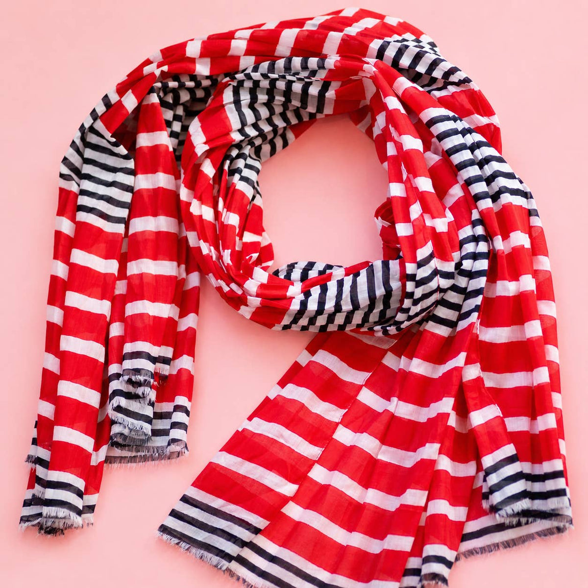 Colourful red, white and navy striped scarf loosely arranged to show off its bold stripes and softly frayed edges.