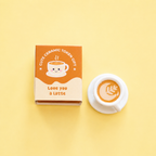 Small ceramic latte token beside its Love You A Latte gift box on a soft butter yellow background.