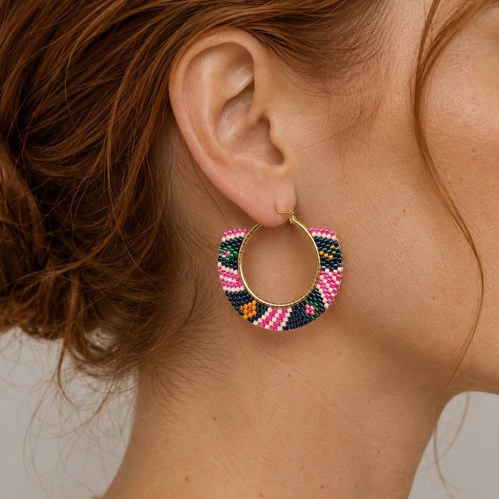 Pink multi geometric beaded hoop earring worn on the ear, showing the colourful glass bead pattern.