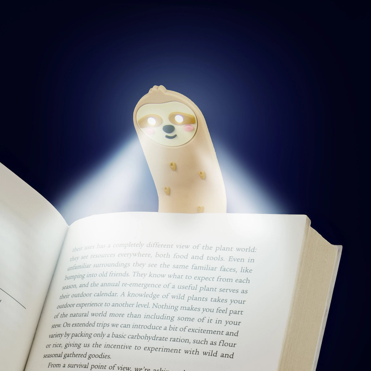 Sloth reading light glowing over the pages of an open book in the dark.
