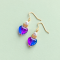 One of a kind gold plated drop earrings with pink and blue glass heart beads, pearl details and small gold crescent moons on a pale green background.