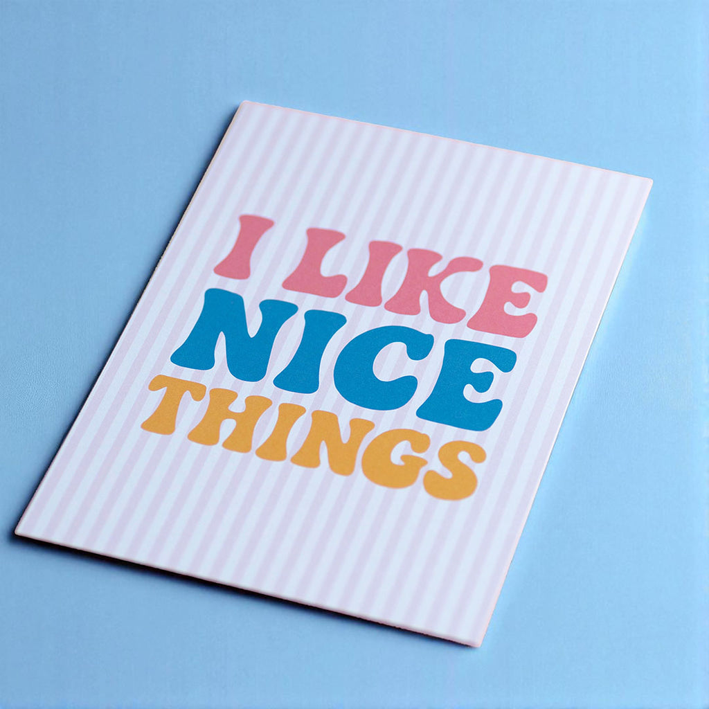 Cheerful I Like Nice Things A5 print with colourful retro lettering and pale pink stripes on a bright blue background.