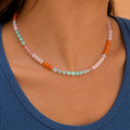 Woman wearing a Coral Reef natural stone bead necklace with coral orange, blush pink, aqua and opalite style beads.