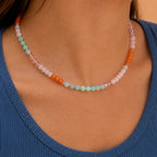 Woman wearing a Coral Reef natural stone bead necklace with coral orange, blush pink, aqua and opalite style beads.